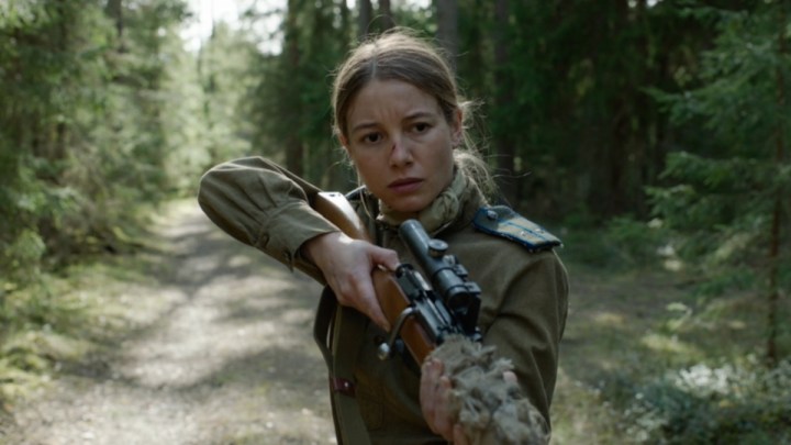 Charlotte Vega segurando uma arma em uma cena de Enterro.