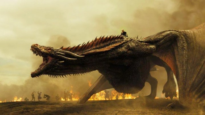 Drogon roaring with Daenerys riding him and fires burning in the background.