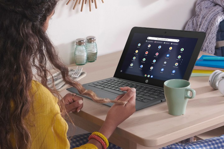 Kadın, HP 11,6 inç Chromebook kullanarak masada oturuyor.