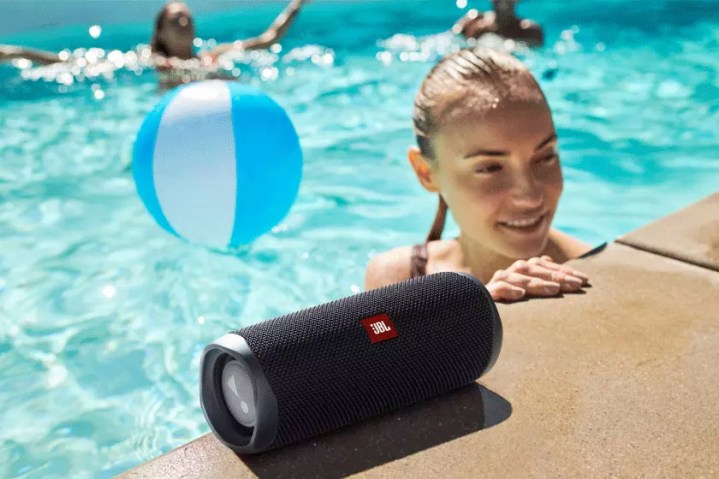 The JBL Flip 5 bluetooth speaker at the edge of a swimming pool.