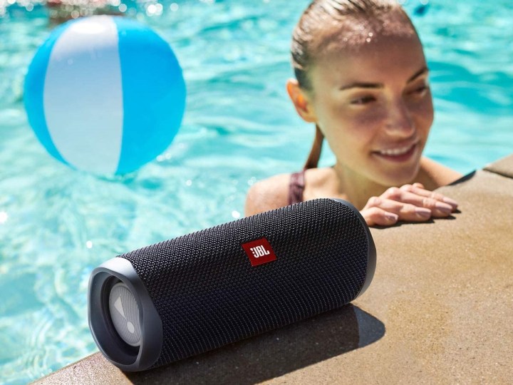 The JBL Flip 5 bluetooth speaker at the edge of a swimming pool.