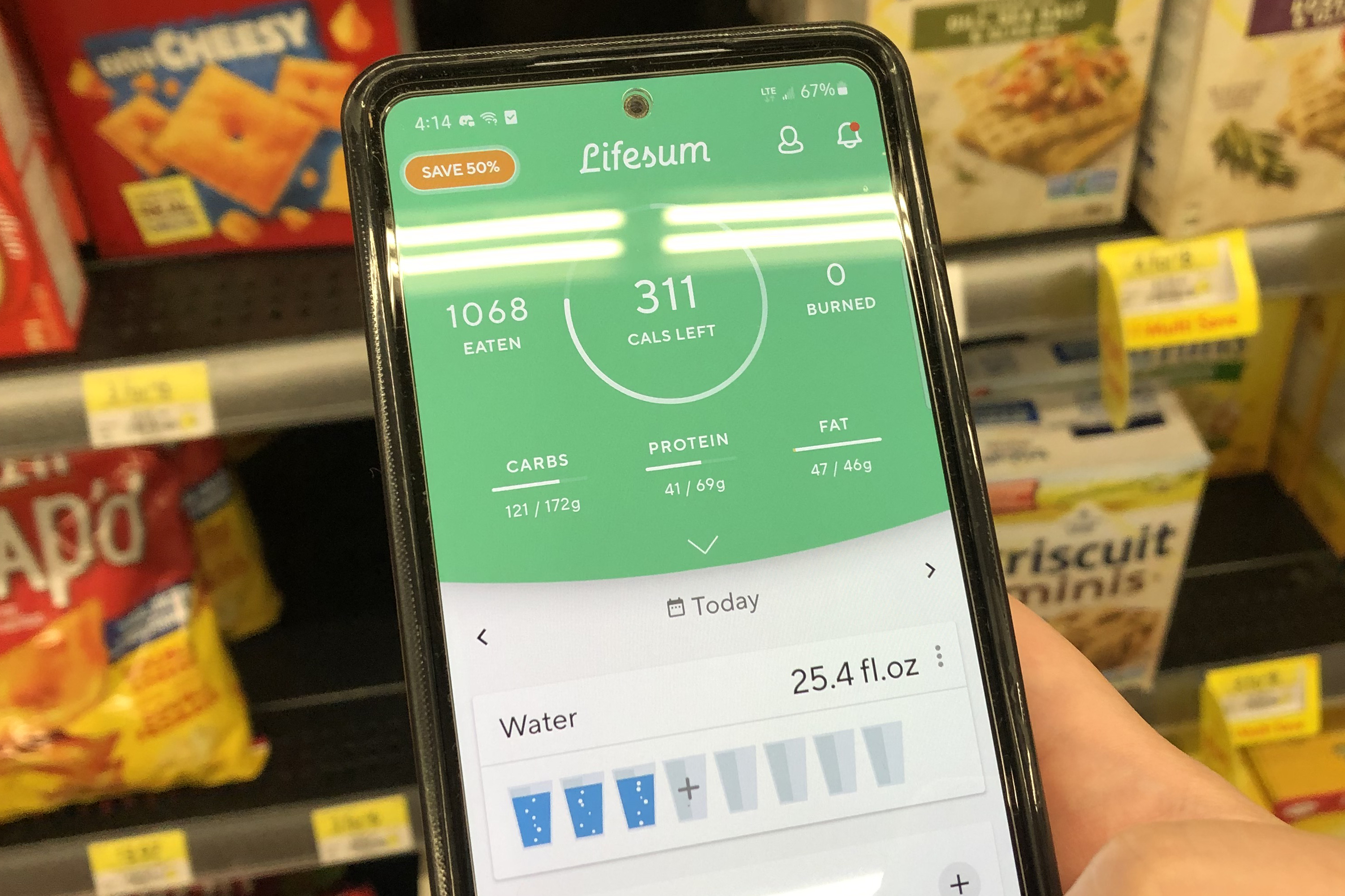 App LifeSum na tela do telefone com bolachas em segundo plano em uma prateleira de loja.