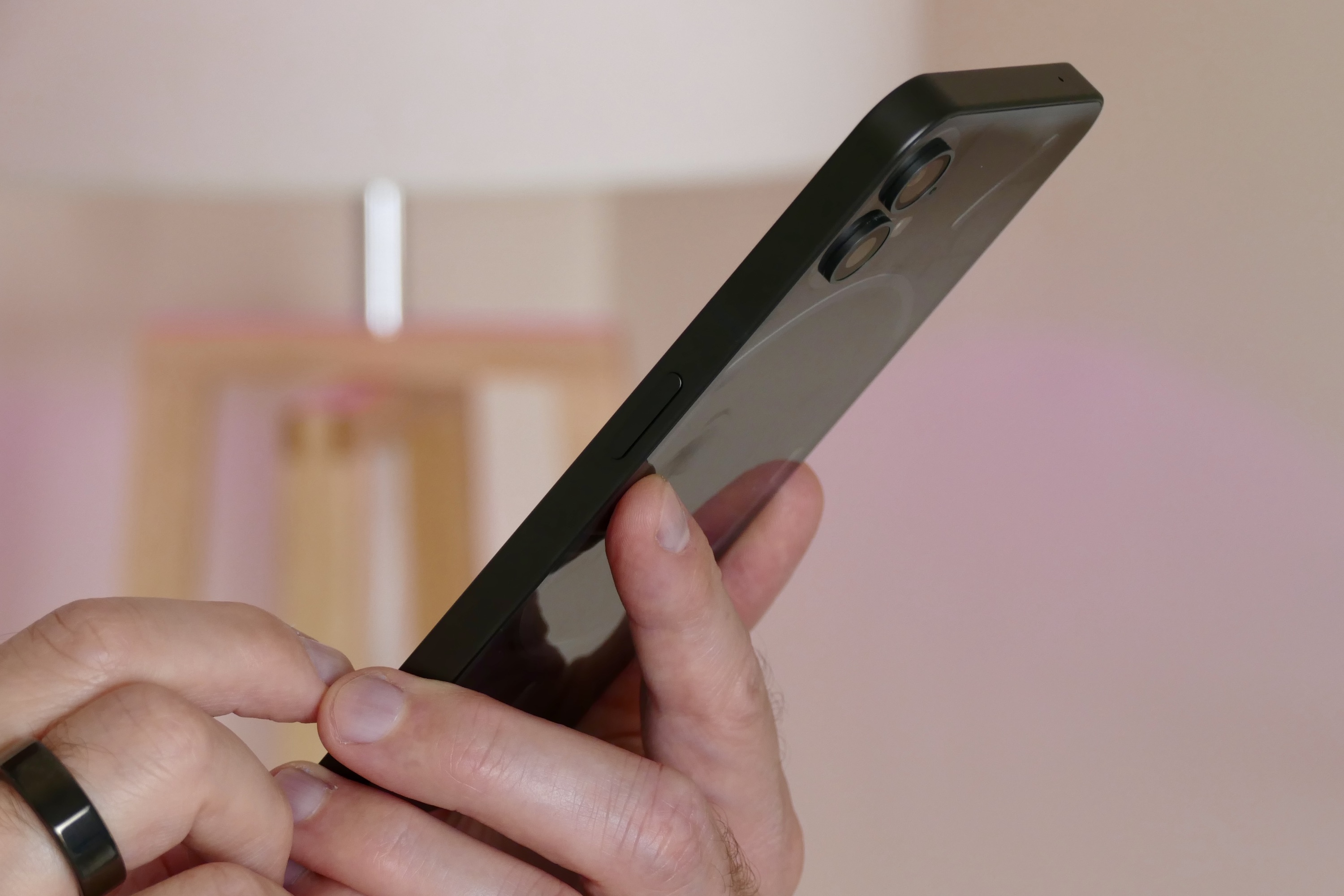 The side of the Nothing Phone 1, held in a mans hand.