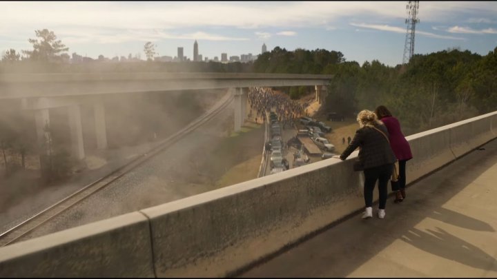 Duas mulheres estão em um viaduto e observam zumbis caminhando em direção a elas em uma cena de Tales of The Walking Dead.