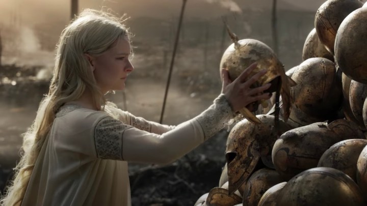  Galadriel putting a helmet on top of a pile in a scene from Lord of the Rings The Rings of Power.