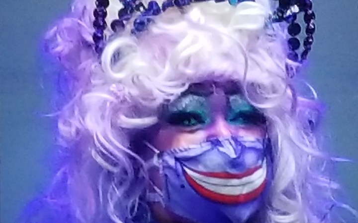 Een cosplay-deelnemer gebruikt haar masker om haar Ursula-cosplay te voltooien.