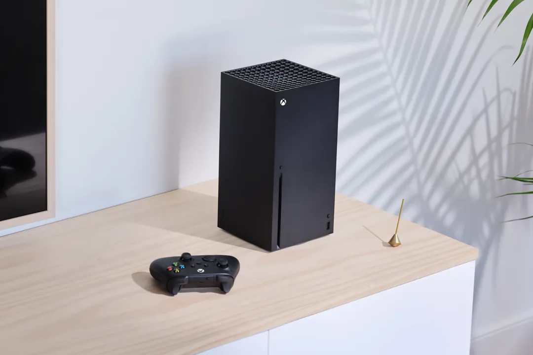 Xbox Series X and a black controller sit on a table.