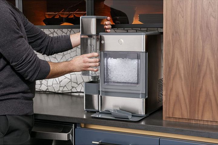 A man fills a glass with ice from the GE Profile Opal Countertop Ice Maker.
