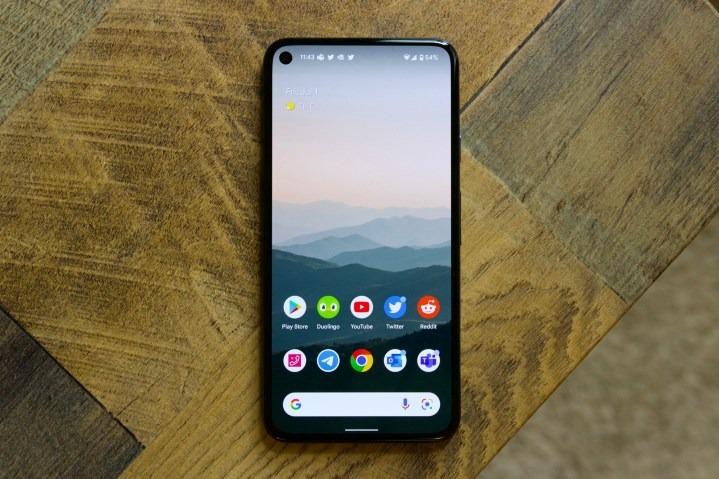 The Google Pixel 5 on a table. We see the front of the phone with the display turned on.