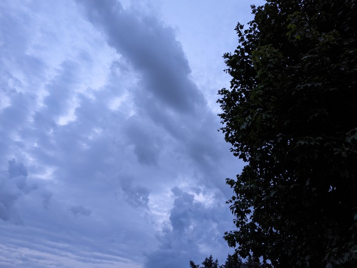 Un cielo tempestoso con nuvole dettagliate. Parte di un albero è visibile nell'angolo destro.