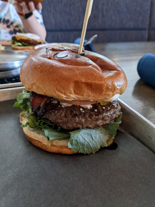 Un grande hamburger su un vassoio di metallo in un bar. Sembra incredibile.