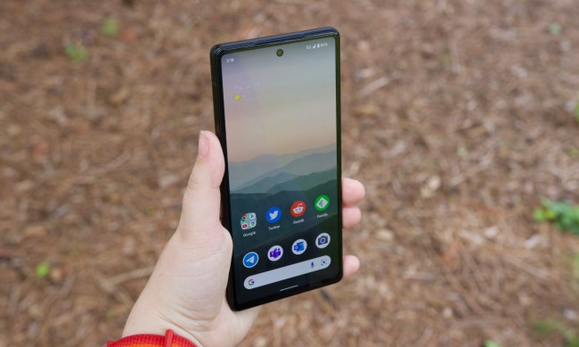 Someone holding the Google Pixel 6a. The display is on and showing the phone's home screen.