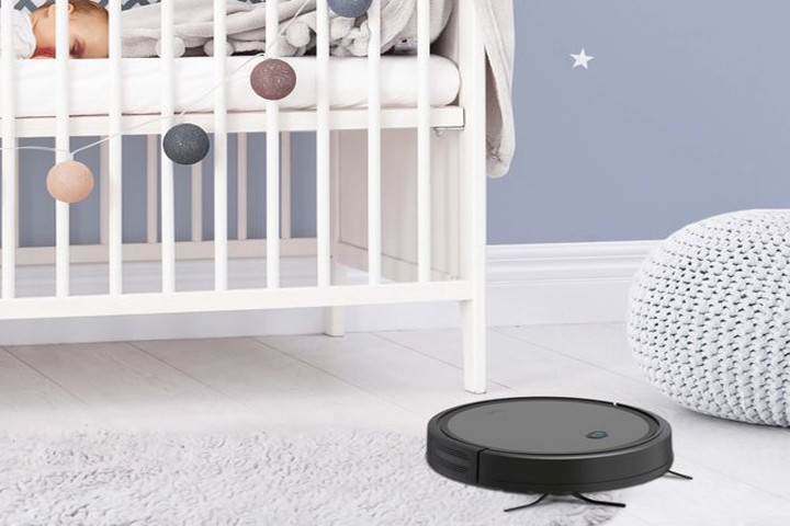 The ionvac SmartClean 2000 robot vacuum vacuums the floor of a nursery while a baby lies asleep in its crib.