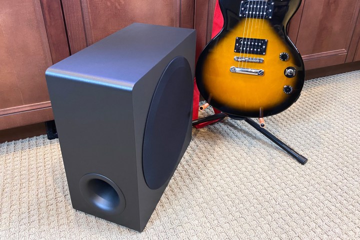 Subwoofer wireless soundbar LG S95QR visto accanto a una chitarra elettrica per bilancia.