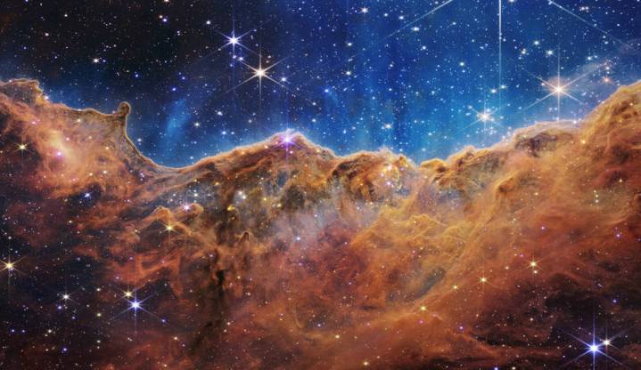 Este paisaje de "montañas" y "valles" salpicados de estrellas brillantes es en realidad el borde de una región cercana, joven y de formación estelar llamada NGC 3324 en la Nebulosa Carina. Capturada en luz infrarroja por el nuevo telescopio espacial James Webb de la NASA, esta imagen revela por primera vez áreas previamente invisibles de nacimiento de estrellas.