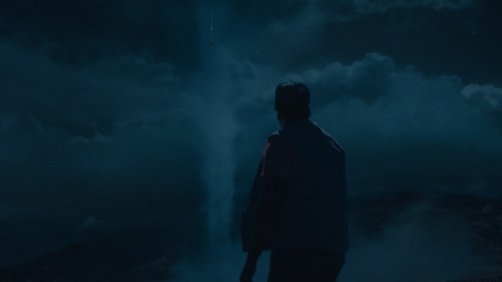 Daniel Kaluuya melihat ke awan corong di langit malam dalam sebuah adegan dari Tidak.