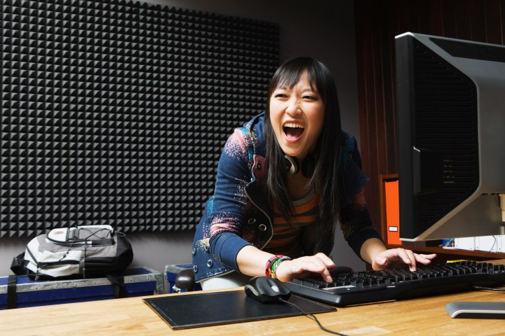 Woman screams for joy while playing games on a PC.