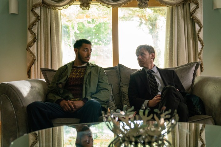 Daryl McCormack e Brian Gleeson estão sentados em um sofá juntos em Bad Sisters da Apple TV+.