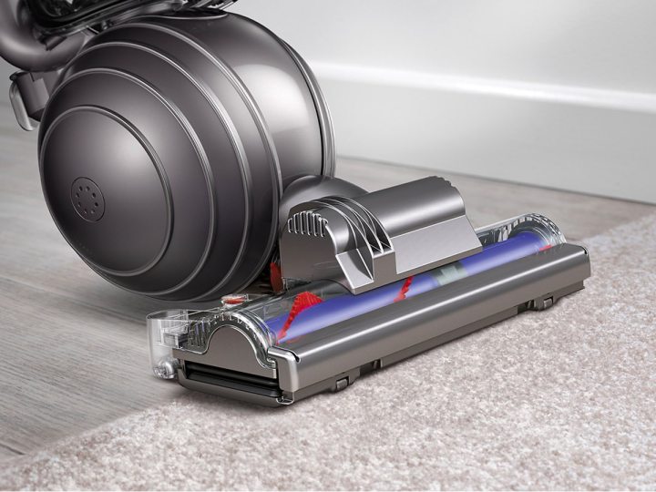 The Dyson Ball Animal vacuum is pushed from hard floor onto carpet.