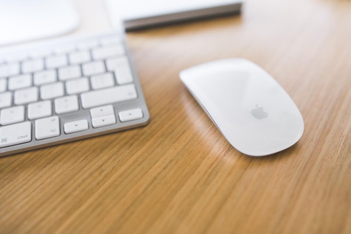 Magic Mouse abutting to a Mac keyboard on a desk.