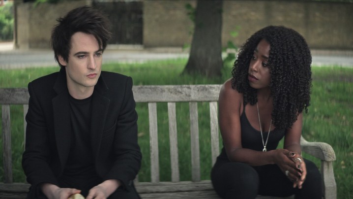 Tom Sturridge sits on a bench with Kirby Howell-Baptiste in a scene from The Sandman.