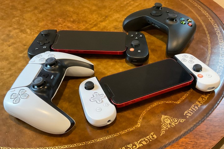 A table holding a DualSense controller, a DualSense Backbone, a regular Backbone, and an Xbox Series X controller.