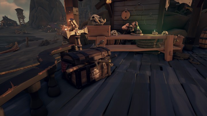 A sea chest sits on a dock, in front of the shipwrights table in Sea of Thieves