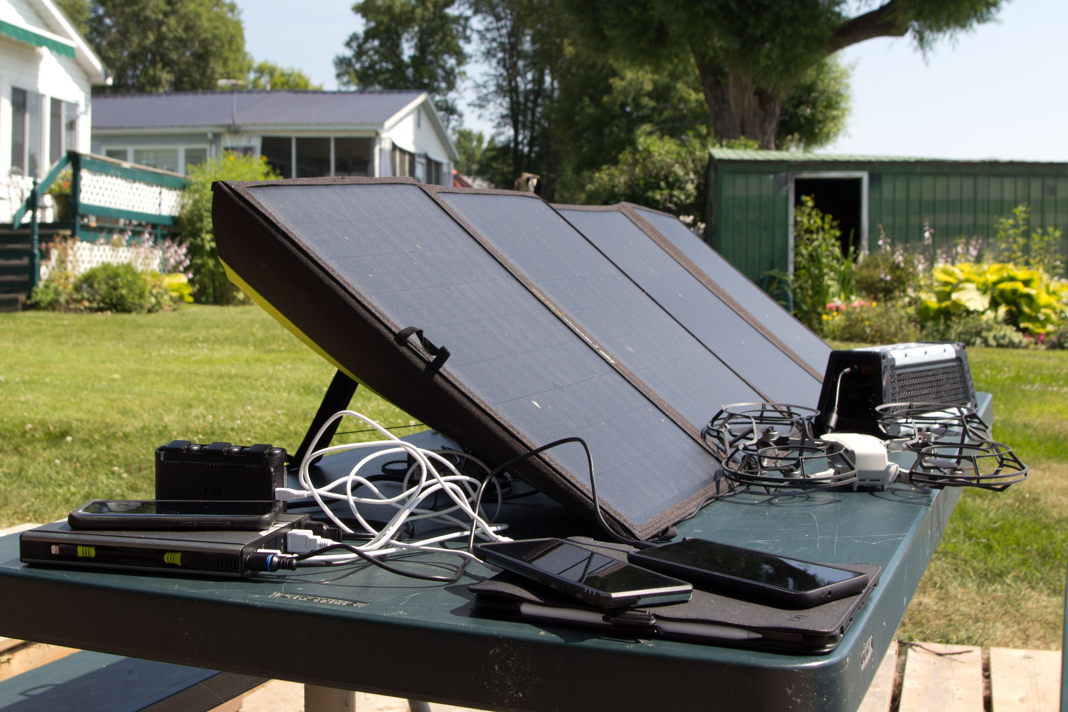Painéis solares Goal Zero Nomad 100 na mesa de piquenique, dispositivos de carregamento. 