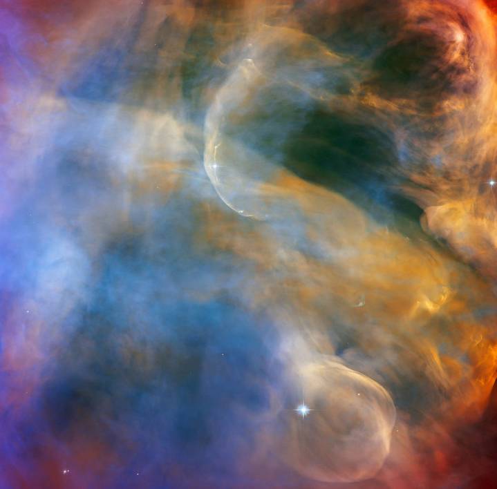 This celestial cloudscape from the NASA/ESA Hubble Space Telescope captures the colorful region in the Orion Nebula surrounding the Herbig-Haro object HH 505. Herbig-Haro objects are luminous regions surrounding newborn stars that form when stellar winds or jets of gas spew from these infant stars creating shockwaves that collide with nearby gas and dust at high speeds. In the case of HH 505, these outflows originate from the star IX Ori, which lies on the outskirts of the Orion Nebula around 1,000 light-years from Earth. The outflows themselves are visible as gracefully curving structures at the top and bottom of this image. Their interaction with the large-scale flow of gas and dust from the core of the nebula distorts them into sinuous curves.