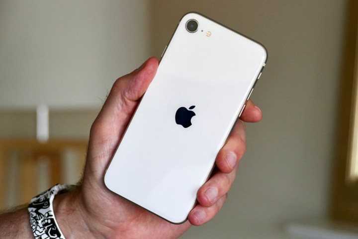 El iPhone SE de Apple (2022) sostenido en la mano de un hombre.