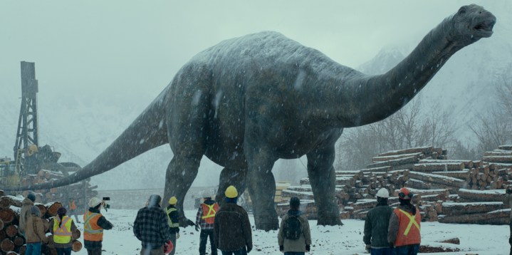 Um grande dinossauro caminha por um canteiro de obras em uma cena de Jurassic World Dominion.