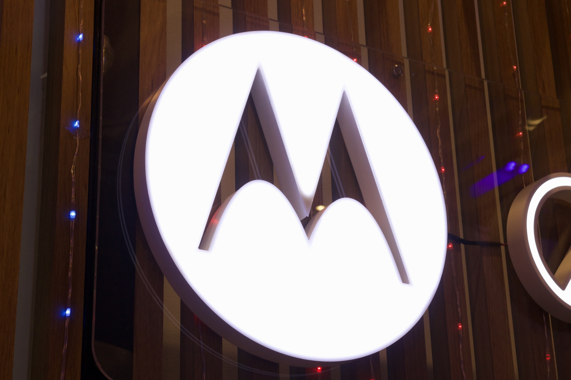 Logotipo blanco de Motorola sobre fondo de madera.