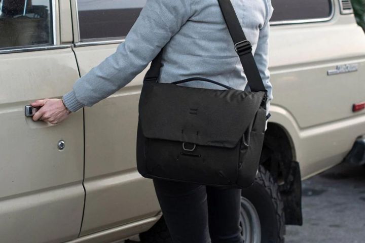 Someone with the Peak Design Everyday Messenger getting into a car.