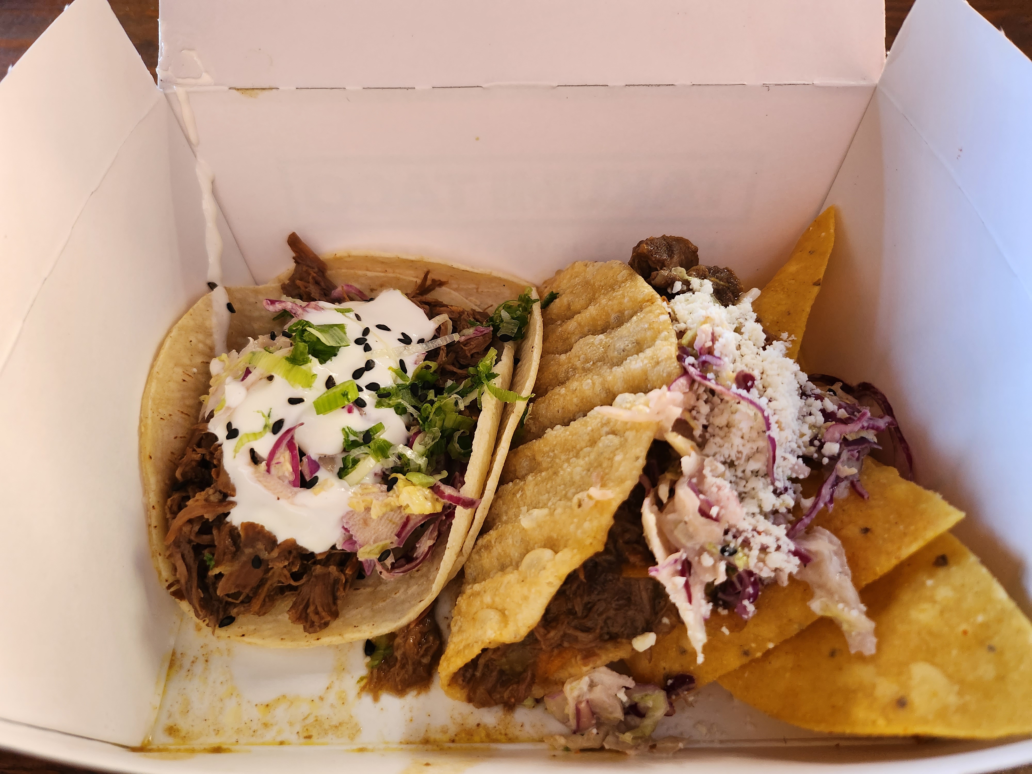 Photo of two tacos in a to-go box.
