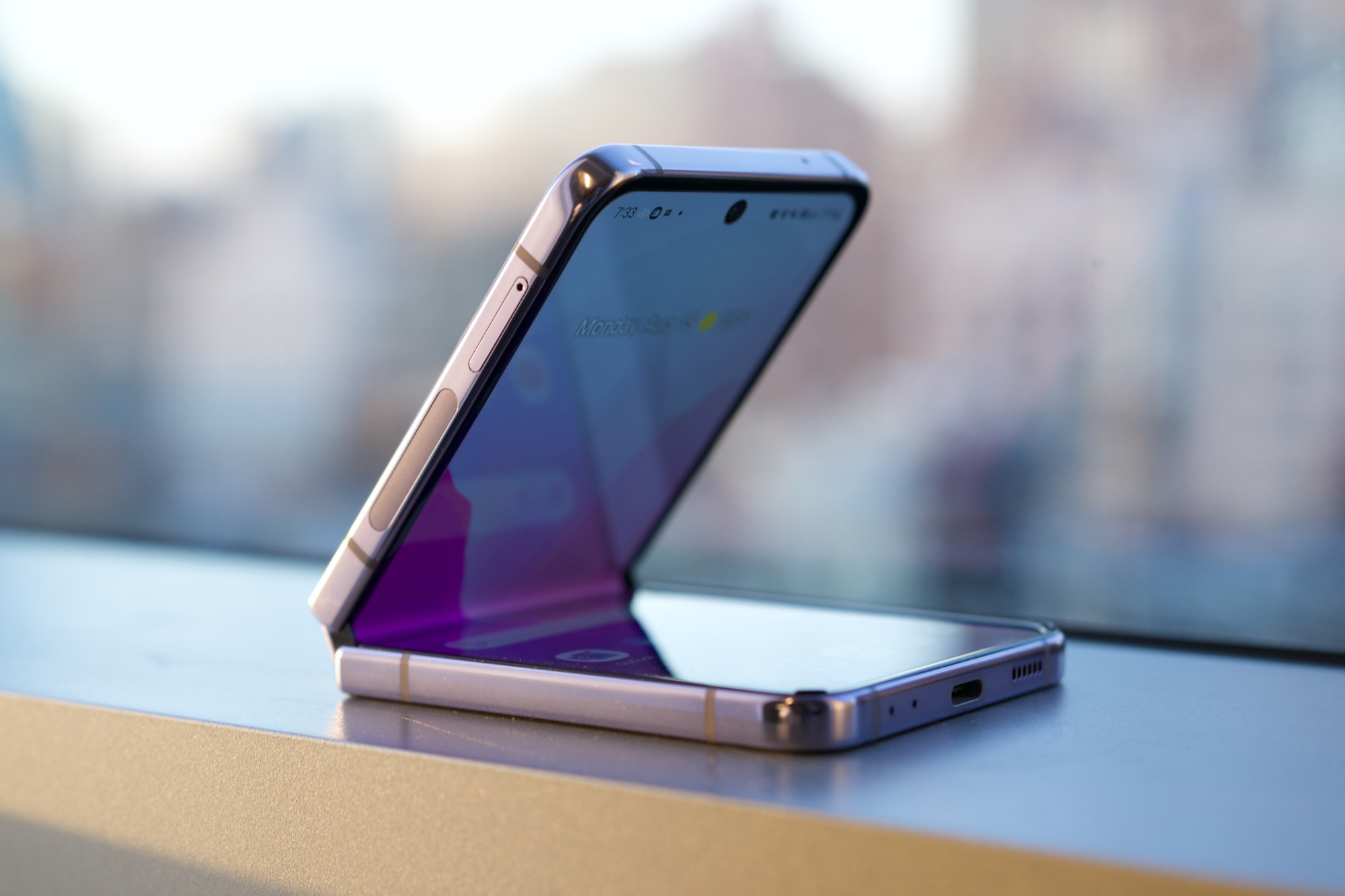 El Samsung Galaxy Z Flip 4 sentado en el alféizar de una ventana.