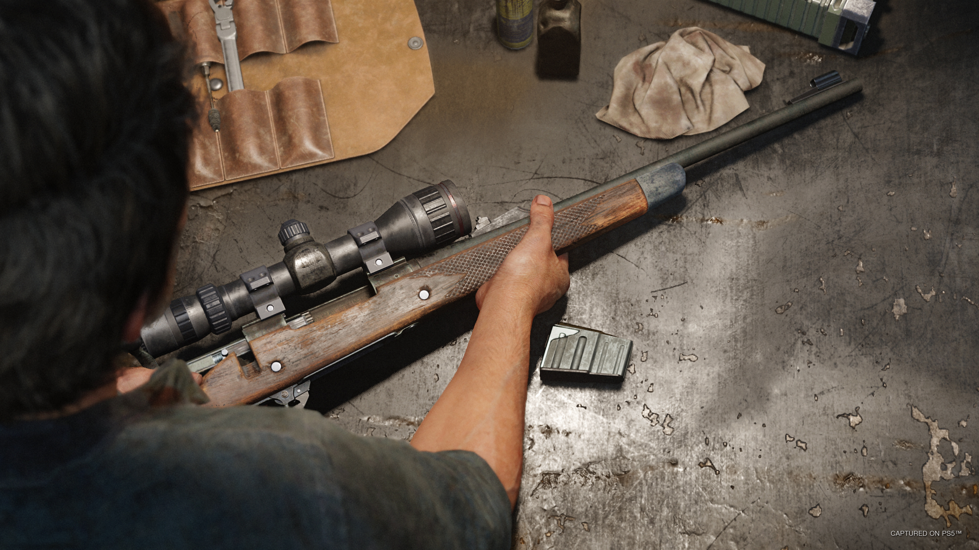Joel coloca un rifle sobre una mesa en The Last of Us Part I.