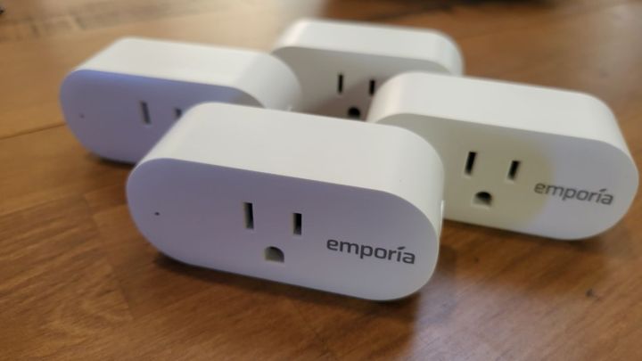 Four Emporia Smart Plugs displayed on a wooden table.