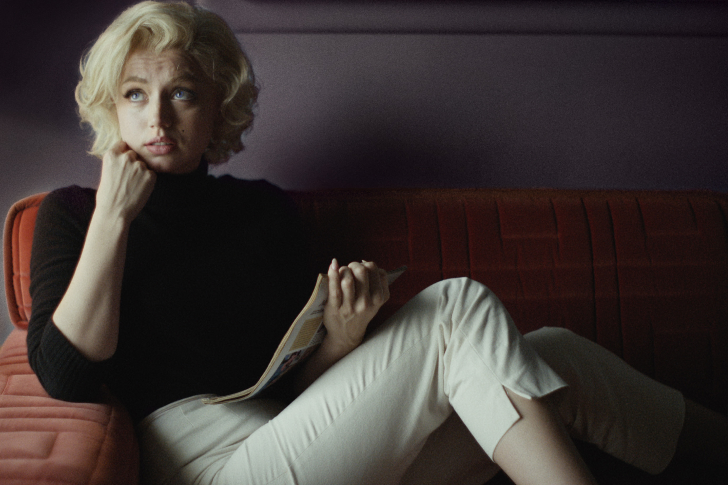 Ana de Armas está sentada em um sofá como Marilyn Monroe em Blonde, da Netflix.