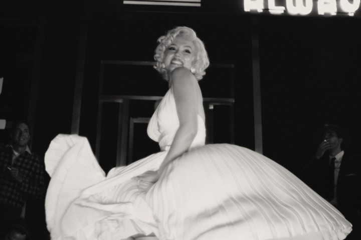 Ana de Armas sorride mentre indossa un vestito bianco fluttuante in Blonde.