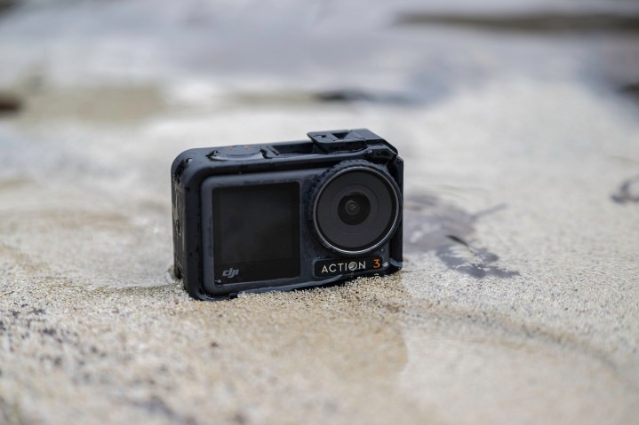 The DJI Osmo Action 3 on a sandy beach in the water.