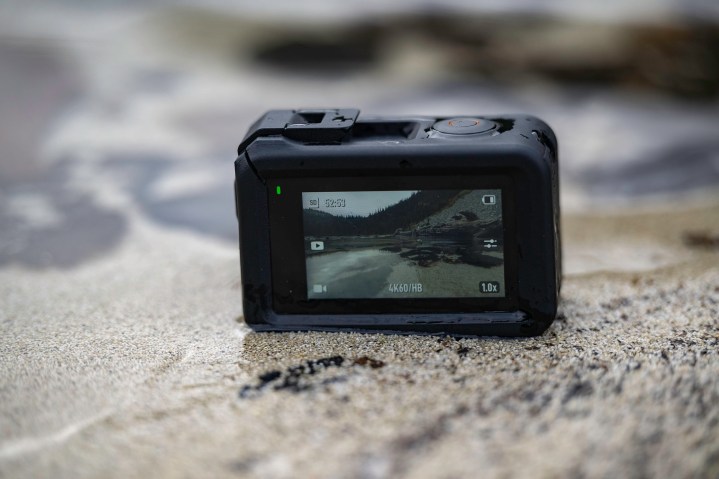 The DJI Osmo Action 3 on a beach halfway in the water.