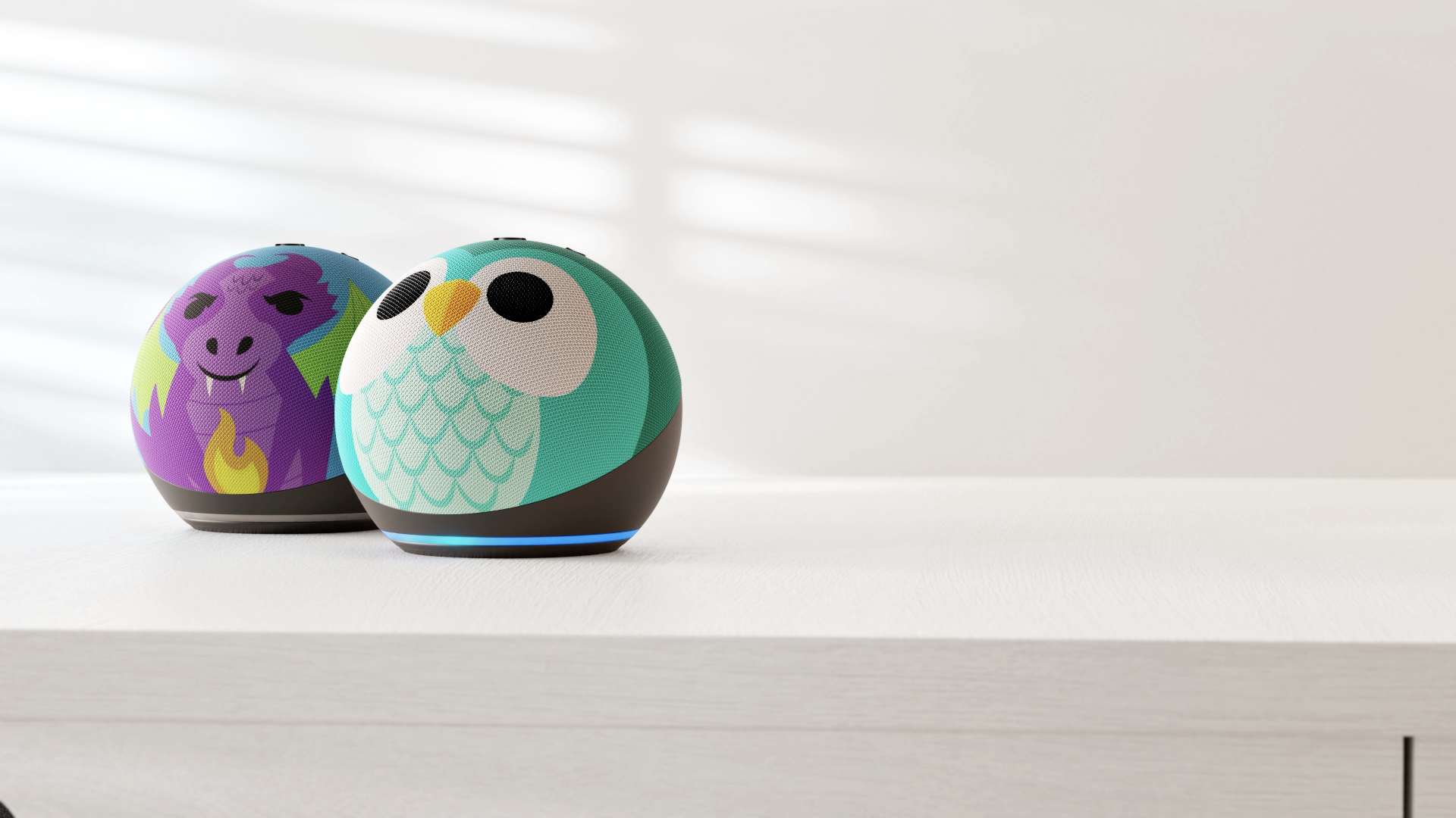 Los diseños Echo Dot Kids Owl and Dragon en una mesa.