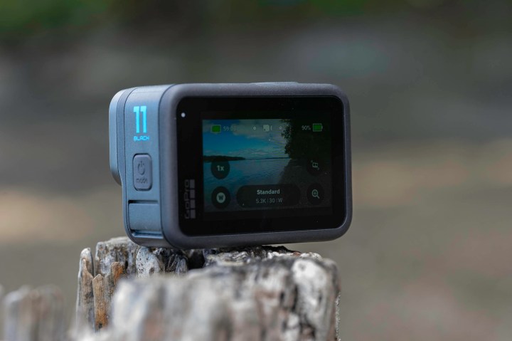 The GoPro Hero 11 Black on an old stump with the screen turned on.