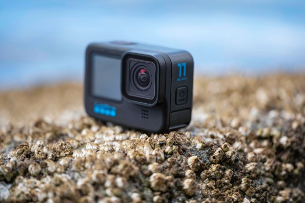 The GoPro Hero 11 Black on a rock with barnacles next to the ocean.