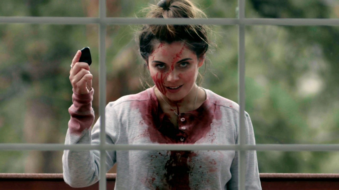 Uma mulher coberta de sangue do lado de fora de uma janela no filme Superhost de 2021.