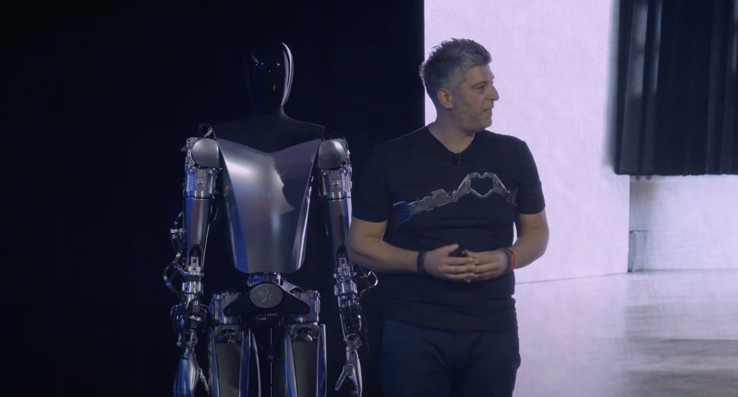 Un empleado de Tesla frente al robot Optimus.