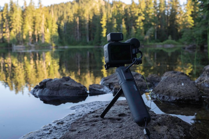 The GoPro Hero 10 Black Creator Edition on a rock beside a lake.