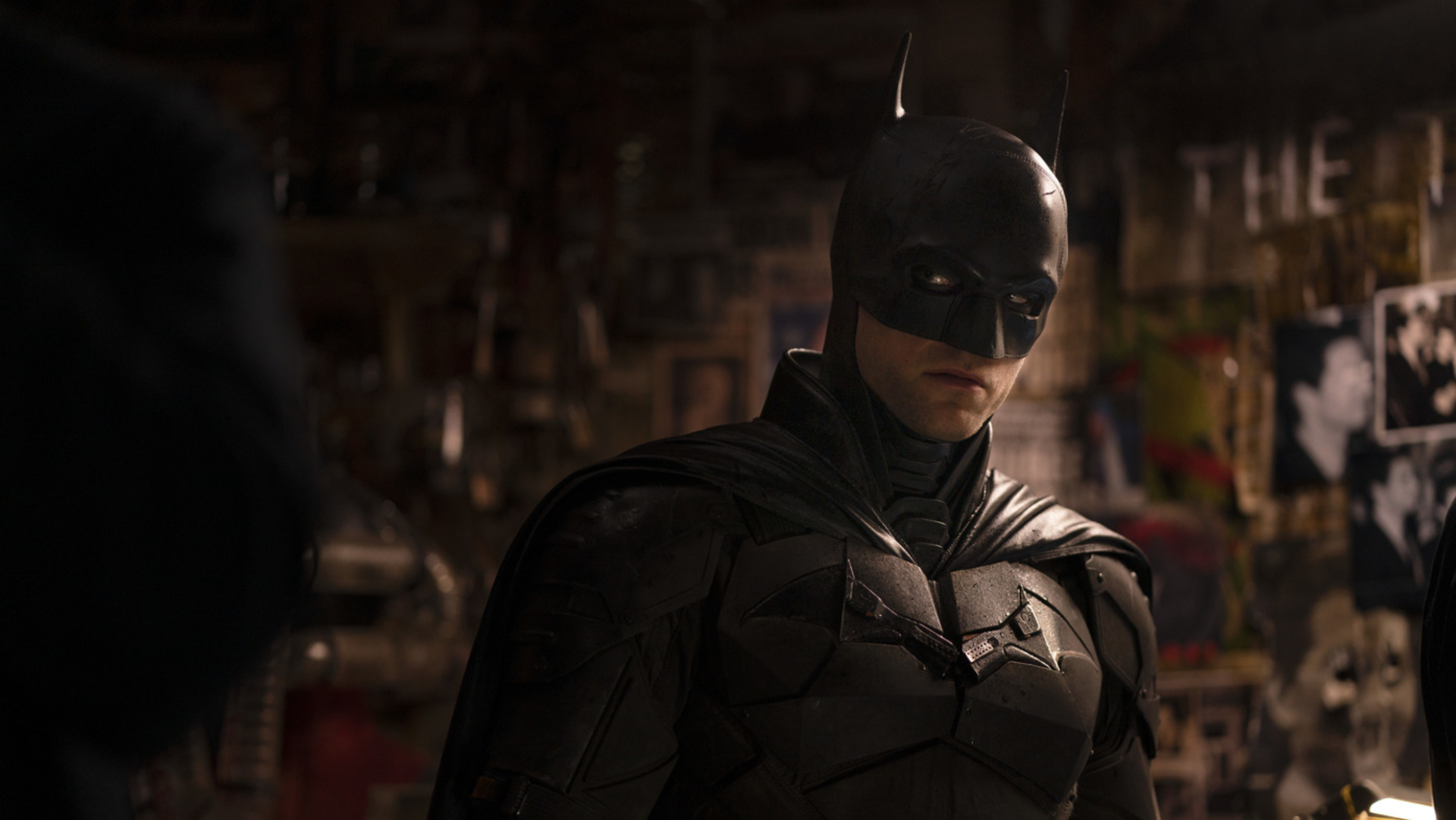 Robert Pattinson como Batman em uma cena de crime mal iluminada.
