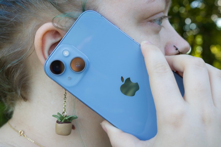 Someone holding an iPhone 14 to their ear.