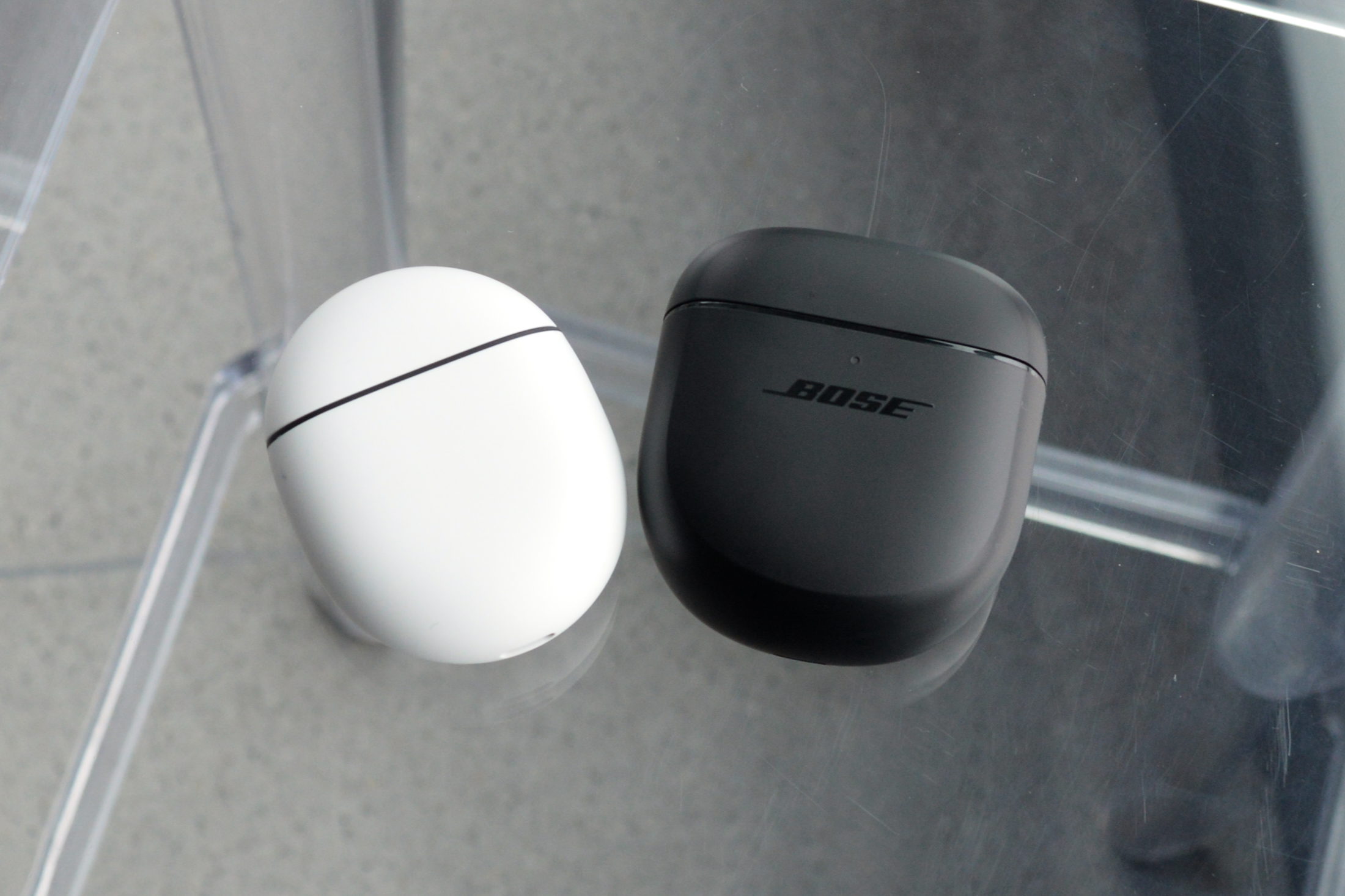 Bose QuietComfort Earbuds II charging case seen next to a Google Pixel Buds Pro charging case for scale.